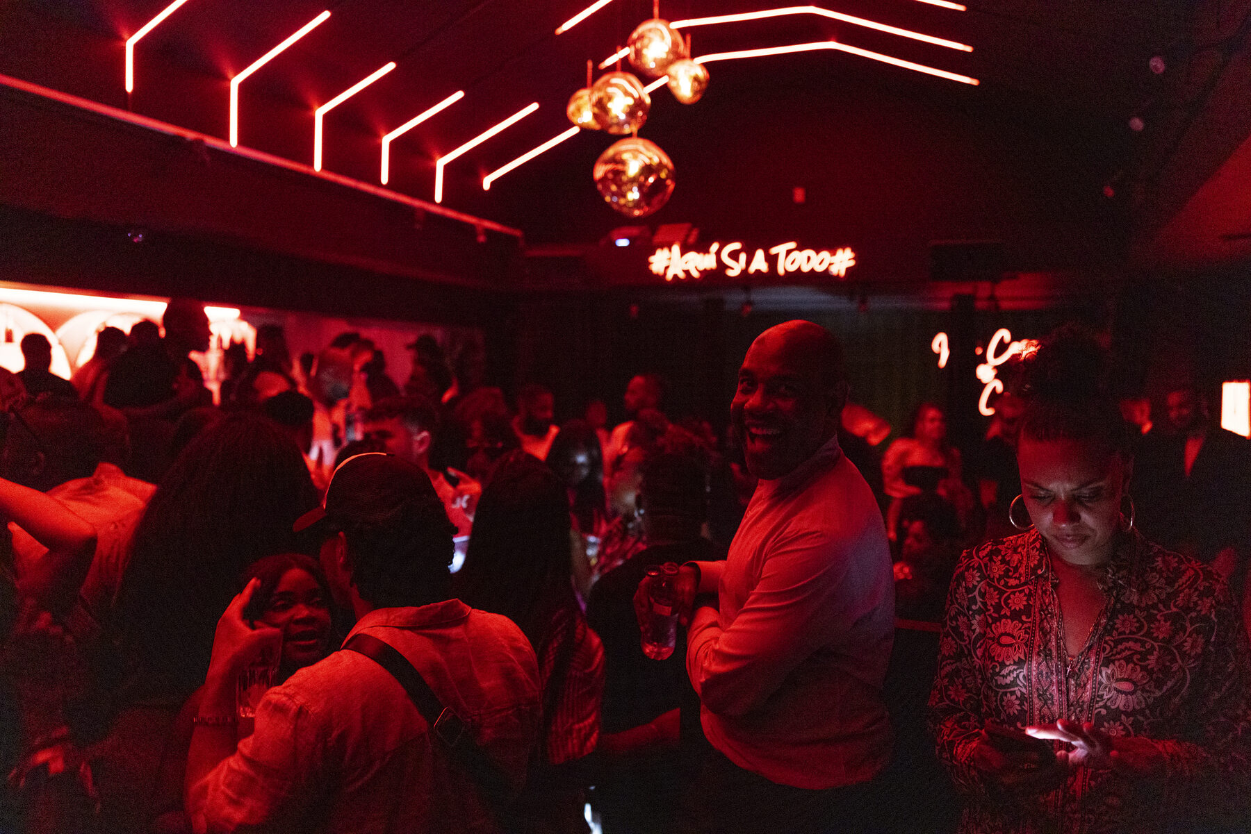 Wide shot of a red-lit venue crowd under neon signage