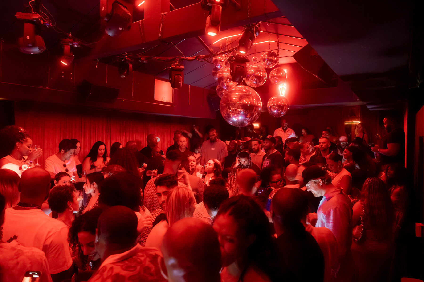 Guests filling a red-lit room beneath the disco balls in Cannes